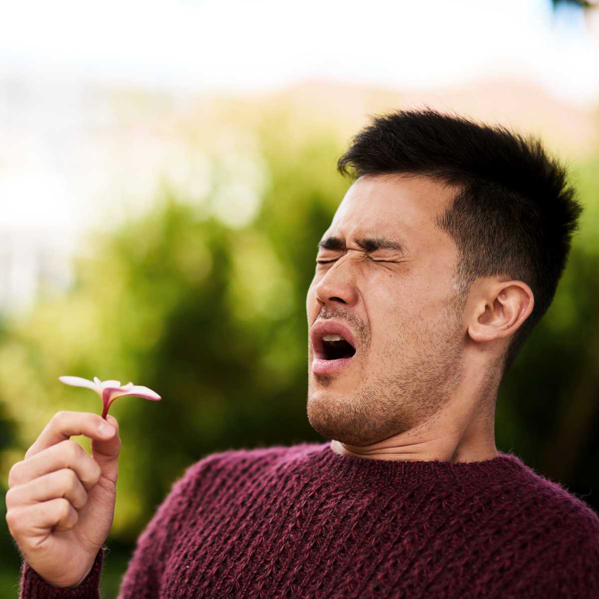 man holding a flower and sneezing