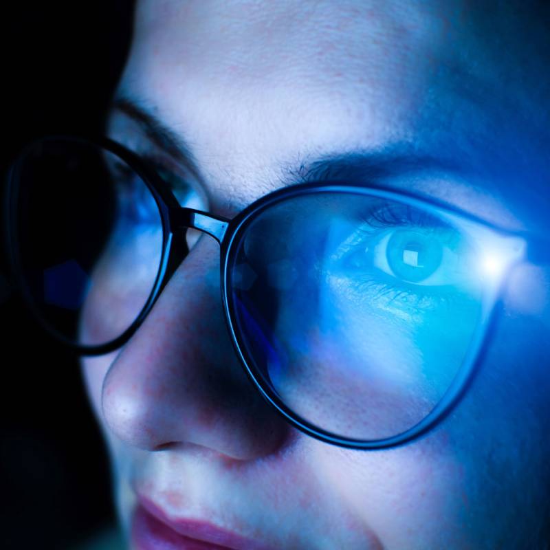 Women with specs with blue light falling on her face