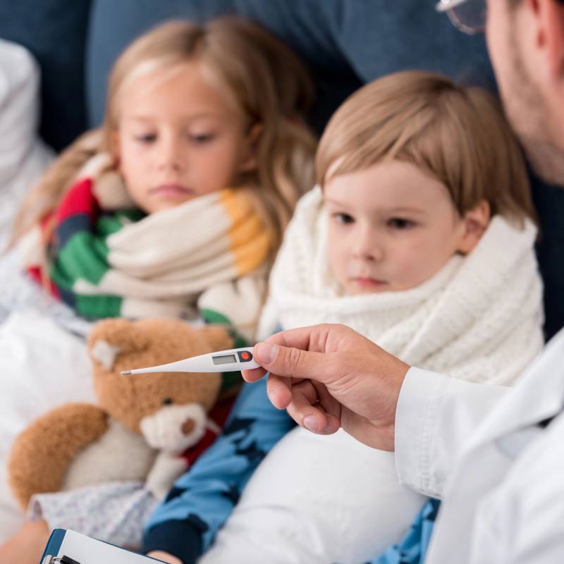 Sick kids with doctor seeing temperature in thermometer.